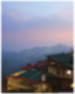 Rooftops in Shimla at sunset with misty hills in the background. Lights twinkle in the distance; a calm, serene atmosphere. Text: Market Street.
