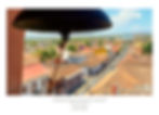 View from a bell tower in Granada, Nicaragua, overlooking colorful rooftops and streets. Bright day, clear sky, and distant mountains.