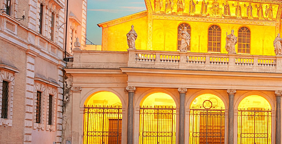 Illuminated Basilica of Santa Maria in Trastevere at sunset, Rome, with a glowing facade and vibrant sky. Text notes location coordinates.