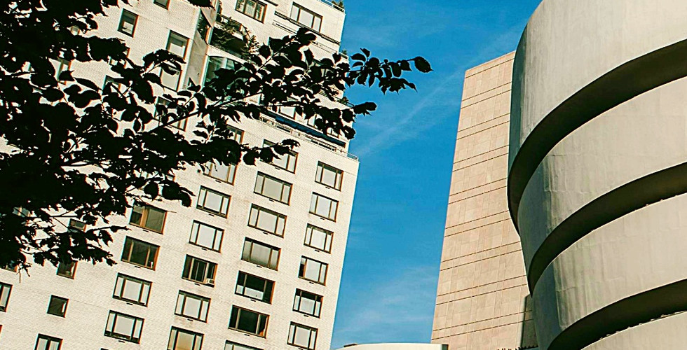 The Guggenheim Museum in NYC, with its iconic spiral design, contrasts against a bright blue sky and nearby buildings. Text: Solomon R. Guggenheim Museum.