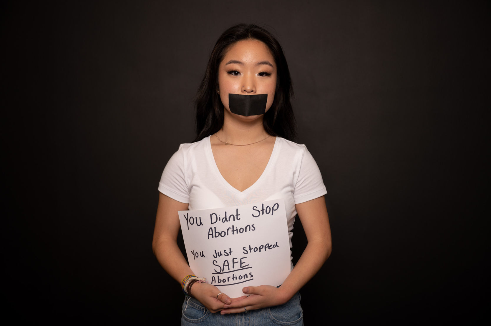Sabrina with black tape covering her mouth  holding a sign close to her body that states, "You didn't stop abortions. You just stopped SAFE abortions."