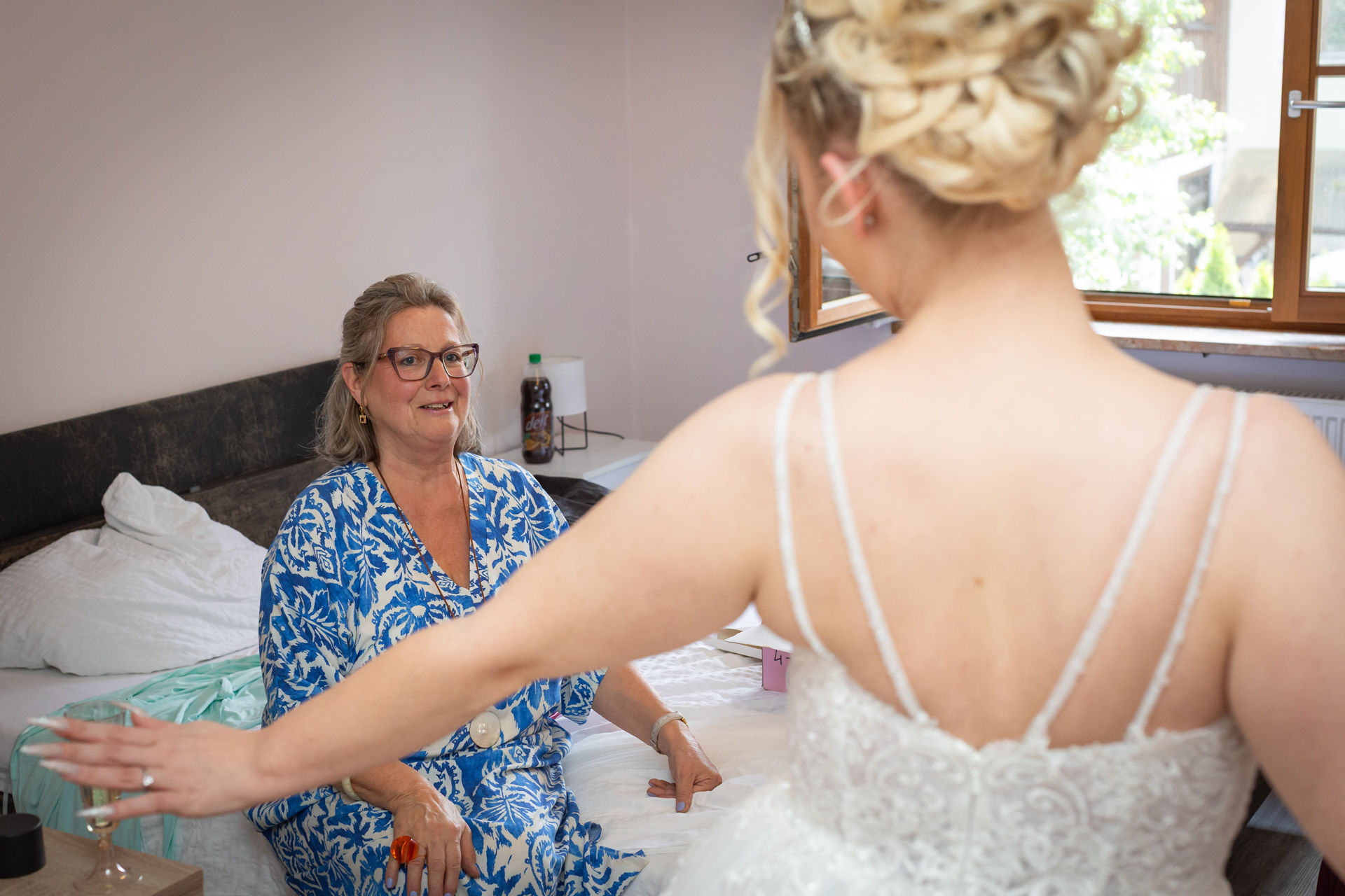 Getting Ready der Braut im Hotel vor der Hochzeit nahe dem Tropenhaus Weihenlinden, ältere Frau sitzt auf Bett, Braut steht schräg vor ihr