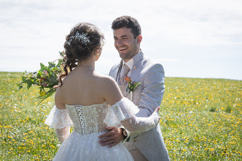 Bräutigam umarmt Braut, lacht, stehen auf Wiese
