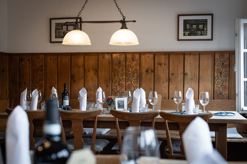 Stube vom Sillberghaus mit Stühlen, Tischen und Hängelampe. Servietten und Weingläser