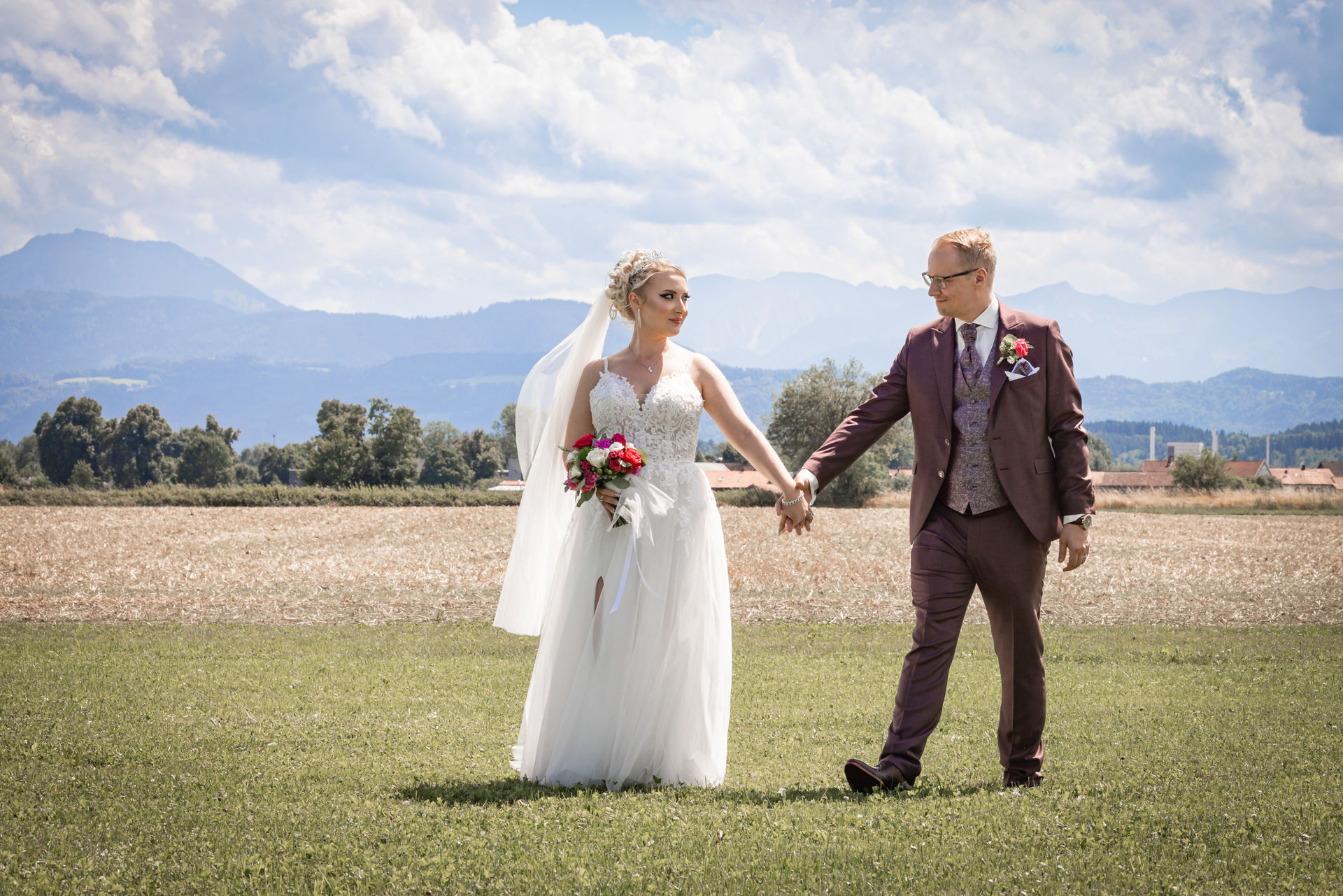 hochzeitsfotografie, bergblick, tropenhaus weihenlinden, Brautpaar Hand in Hand geht über wiese