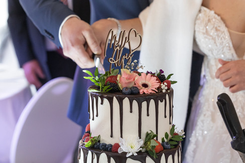 Hochzeitstorte, die angeschnitten wird, es sind nur Hände zusehen, die die Torte anschneiden