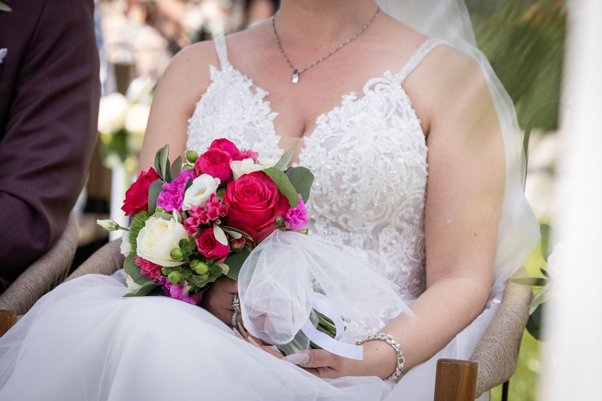 Hochzeit mit freier Trauung draußen im Tropenhaus Weihenlinden in Oberbayern, Braut sitzt, hat Brautstrauss auf dem Schoss