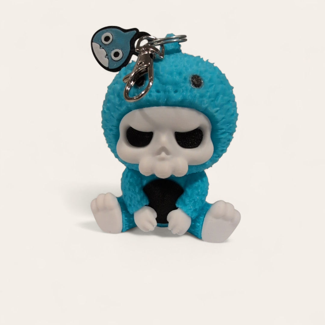 Skull-faced keychain with blue costume and seated pose.
