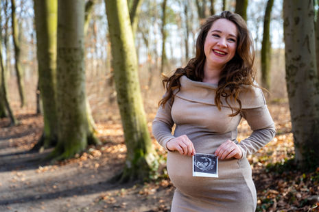 Schwangere Frau im Wald mit Ultraschallbild, Schwangerschaft. Glückliche Frau im Herbstwald