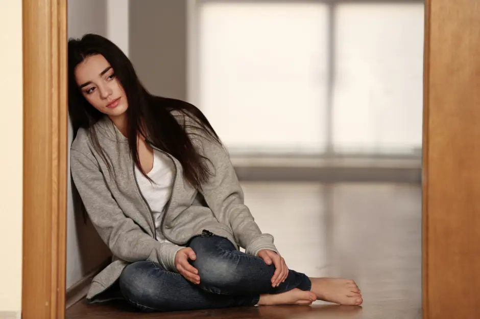 sad woman seated on the floor leaning on the door opening
