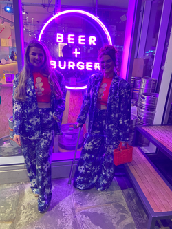The Sugarcoated Sisters posing candidly outside a restaurant in London wearing matching patterned suits.
