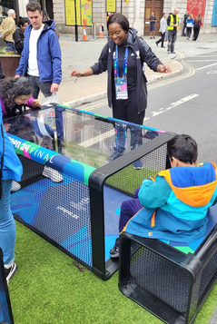 Akua Opong guiding others during a sports event in London standing in front of a net in the middle of a closed off street