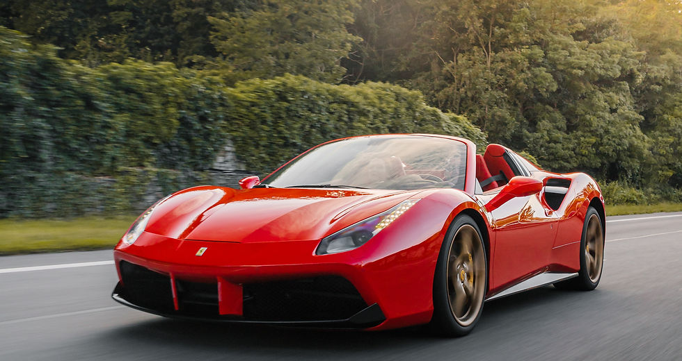 Red Ferrari convertible speeding along a forest road, with motion blur and sunlit trees in the background.