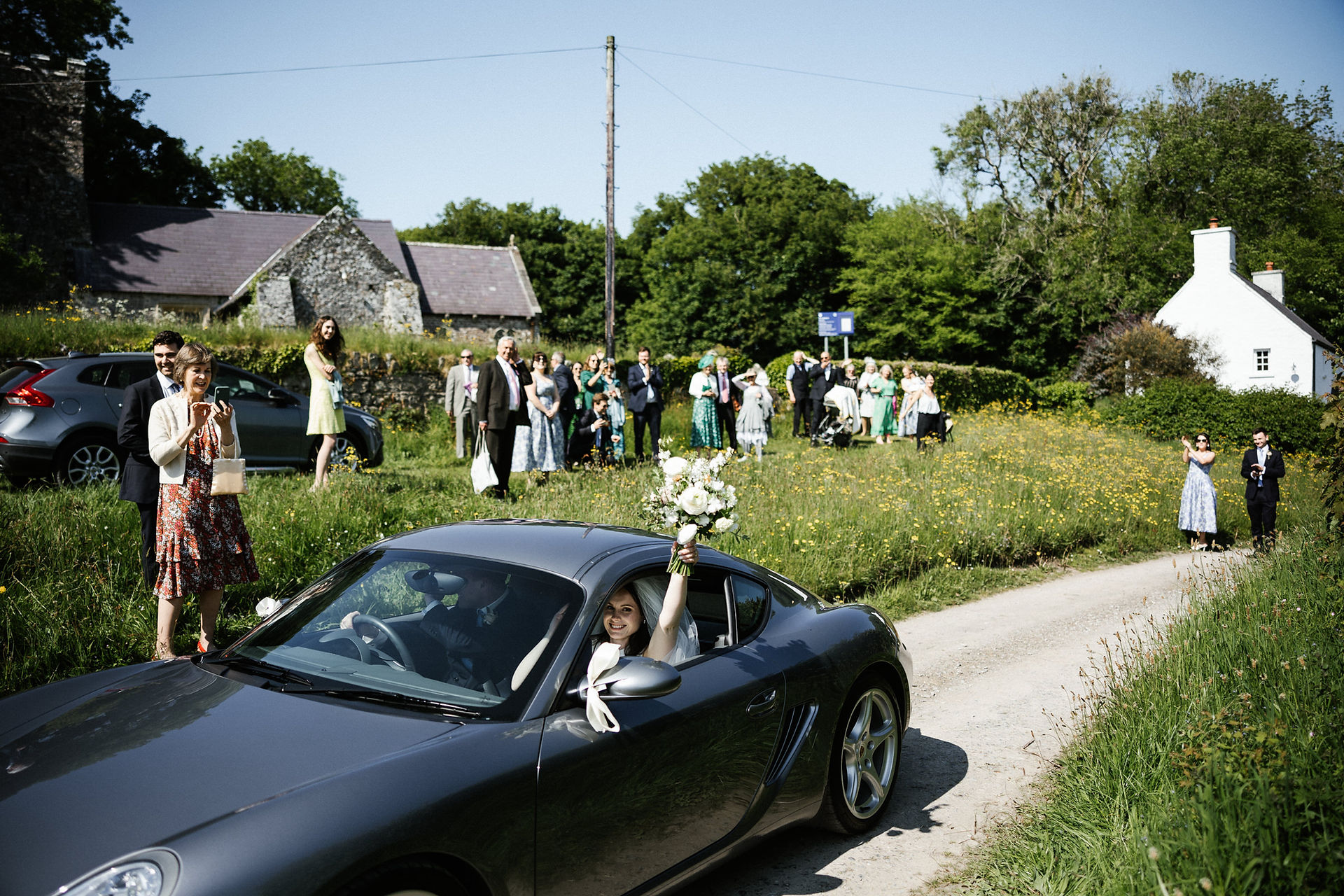 Bride and groom leaving the church in a sports car.