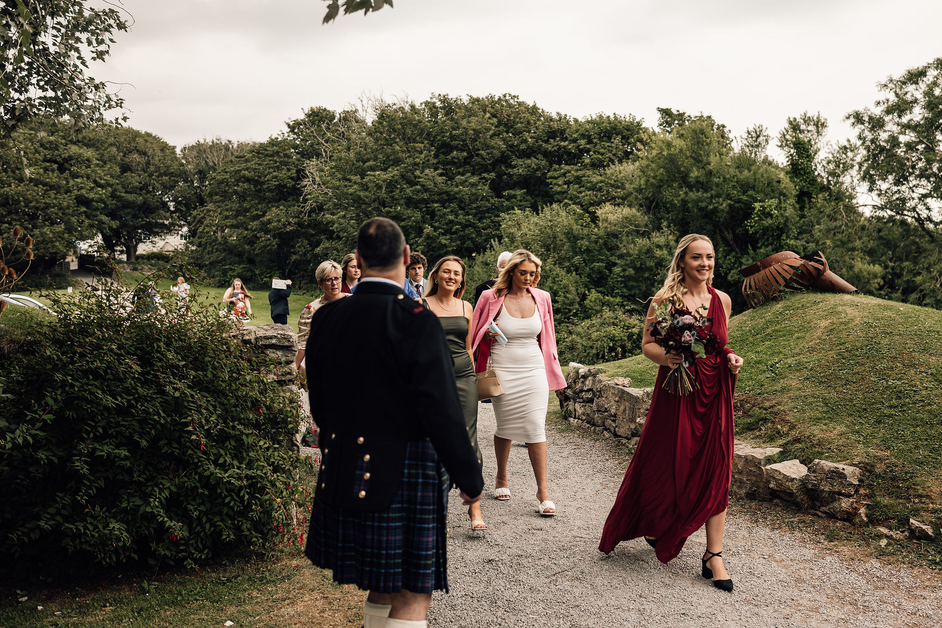 Bridesmaid and wedding party walking down a driveway towards the wedding venue.