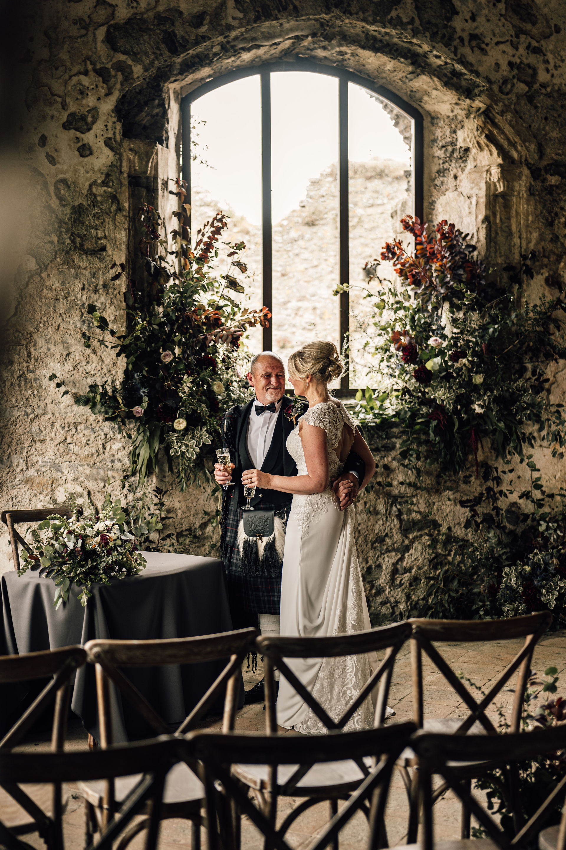 Bride and groom surrounded by large wild floral displays in autumnal colours.