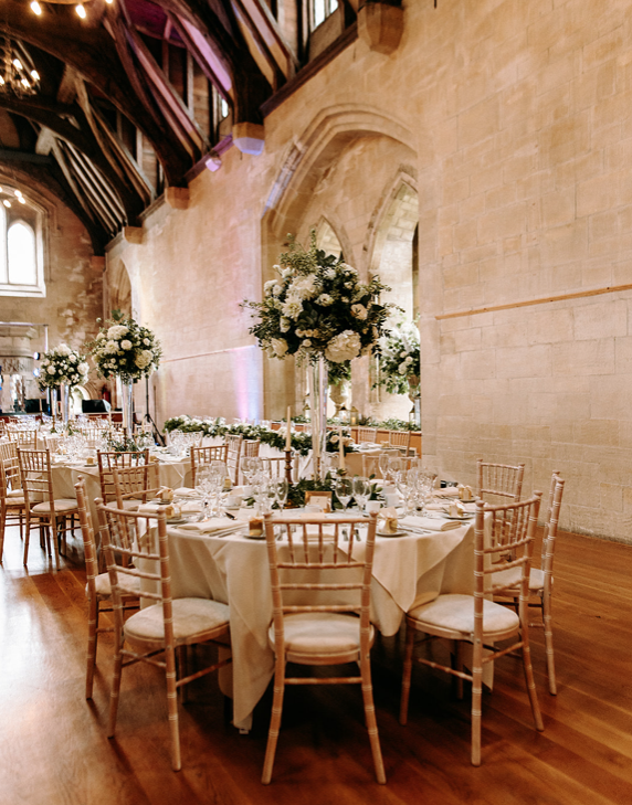 Round tables dressed with flowers and candles for a wedding reception.