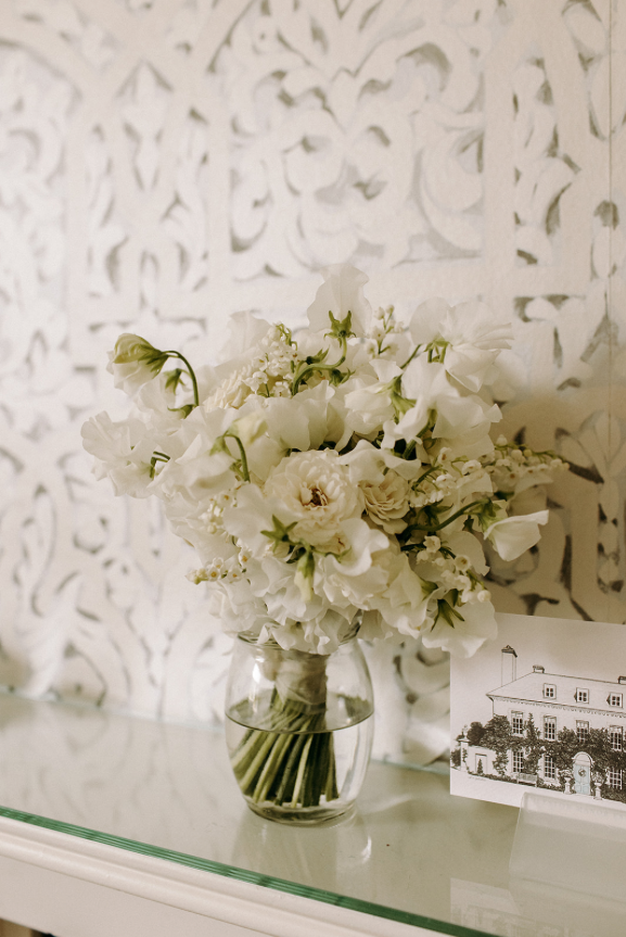 White bouquet of flowers on a mantel piece.