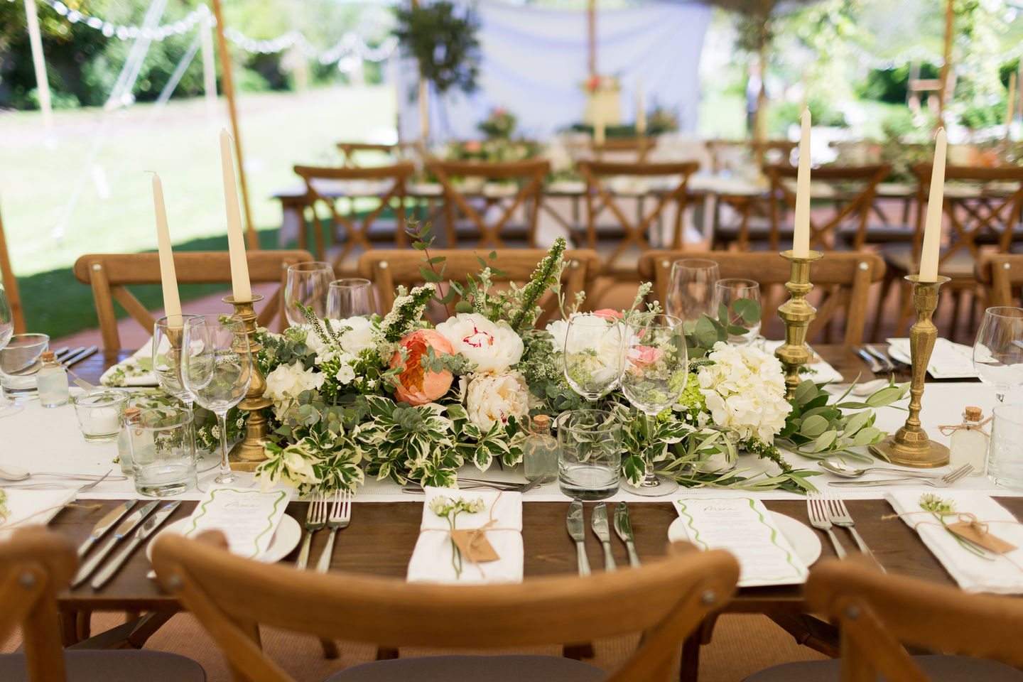 Marquee wedding table heavily decorated with flowers and candles.
