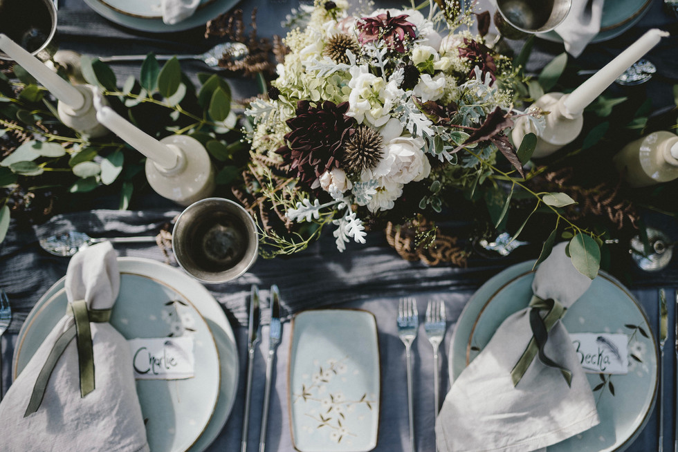 Wedding table heavily decorated with grey linens, flowers and candles.