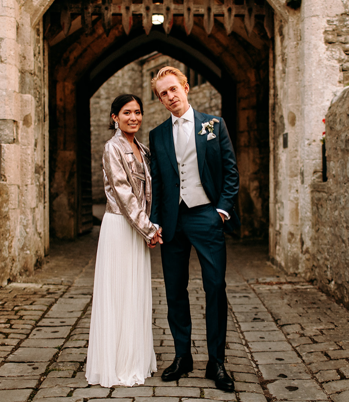Bride and groom standing at the entrance of a castle.