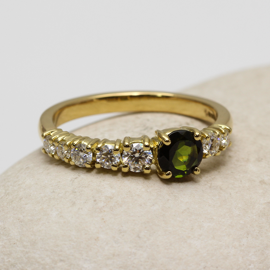 A gold ring with a green emerald and diamonds.