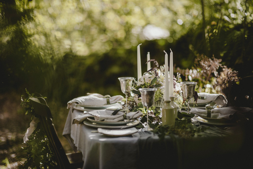 Alfresco wedding table heavily decorated with flowers and candles.