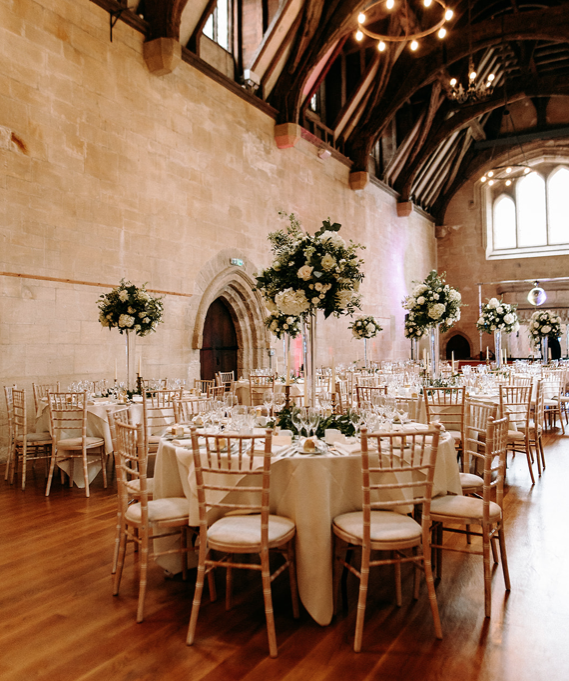 Round tables dressed with flowers and candles for a wedding breakfast.