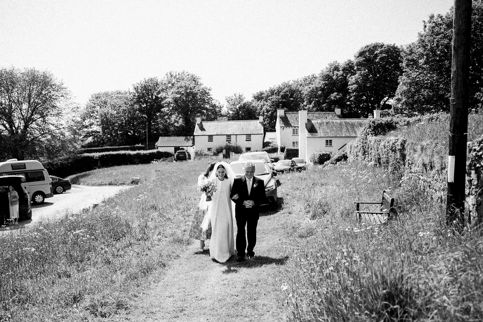 Bride and her father approaching a village church.