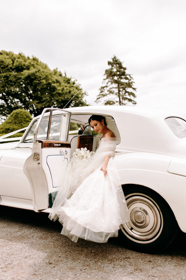 Bride in her white wedding car.