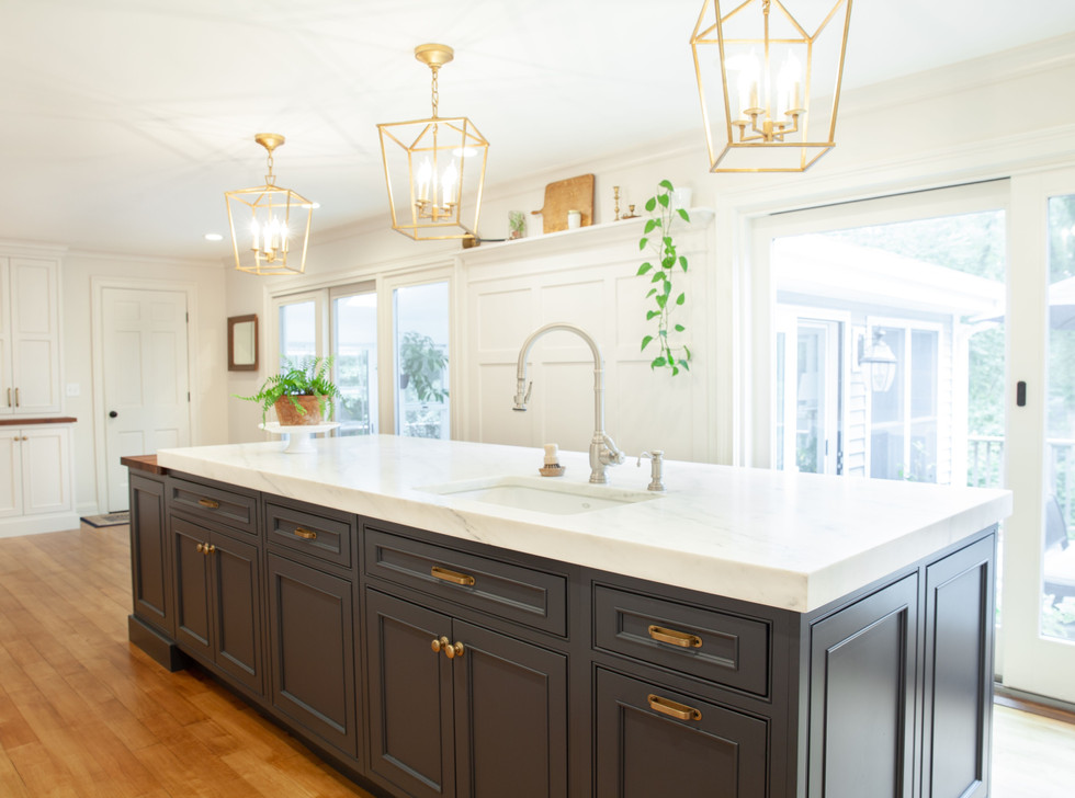 This traditional farmhouse kitchen renovation is truly one of a kind. The Connecticut home is surrounded by beautiful gardens, well curated antiques and a lovely greenhouse where the owners do most of their planting. The kitchen and living area sits off the greenhouse, so we wanted many elements of this renovation to mirror the bespoke character of the home.
All cabinetry is custom Durasupreme, with a gorgeous “Linen White” painted maple upper and perimeter, and contrasting island in Durasupreme’s curated “Cyberspace”. The island features a walnut butcher block extension with an apothecary custom drawer base. The island and cabinetry are anchored by a stunning 2” mitered Olympian Danby marble countertop, that carries up as the backsplash seamlessly.
Other features include all Wolf and Subzero appliances, matching built-in cabinetry and open shelving anchored around the fireplace in the living area, custom wainscoting and decorative paneling, and 100% English Brass hardware and finishes.