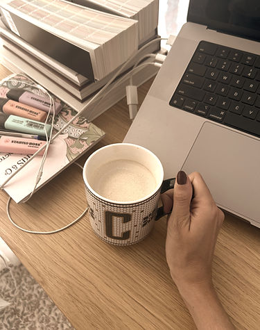 Interior designer’s workspace at Camila Interiors featuring a laptop, coffee mug, design books, fabric samples