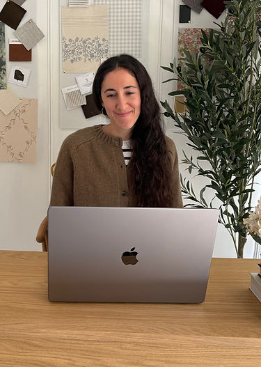 Camila, founder and interior designer of Camila Interiors, working on her laptop in her design studio