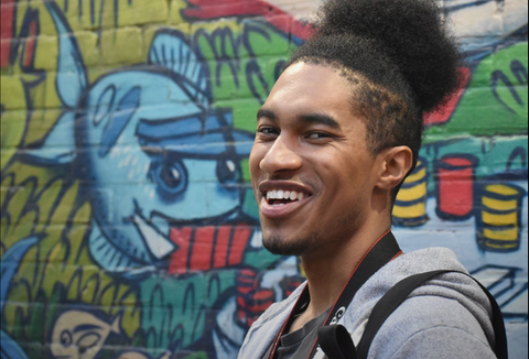 Homme souriant devant un graffiti coloré
