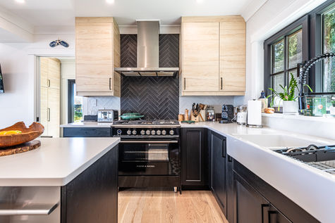 kitchen island on the left with a built-it dishwasher, gorgeous stove and cabinets in the rear, elegant black trimmed windows on the right