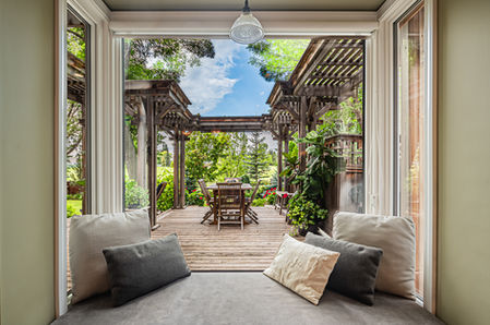 bay window overlooking a west edmonton backyard patio surrounded by plush plants - blue sky peeking through - real estate photography