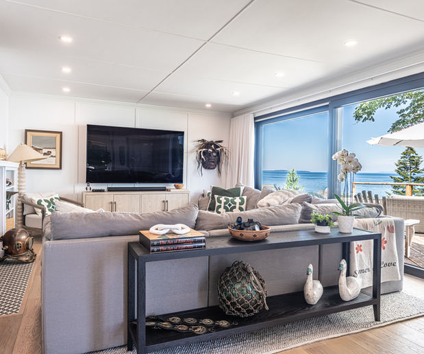 Modern living room, large TV, comfortable sofa, expansive ocean view.