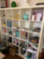 A cubed shelving unit before it has been decluttered with different random objects on each square sh