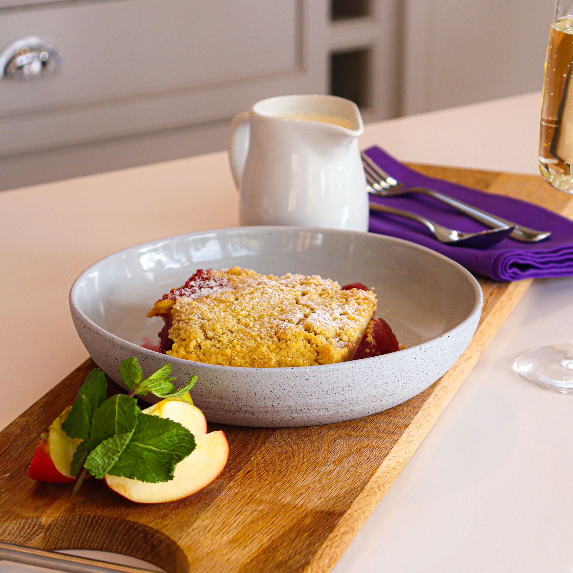 Apple and blackberry crumble on a wooden board garnished with fresh mint