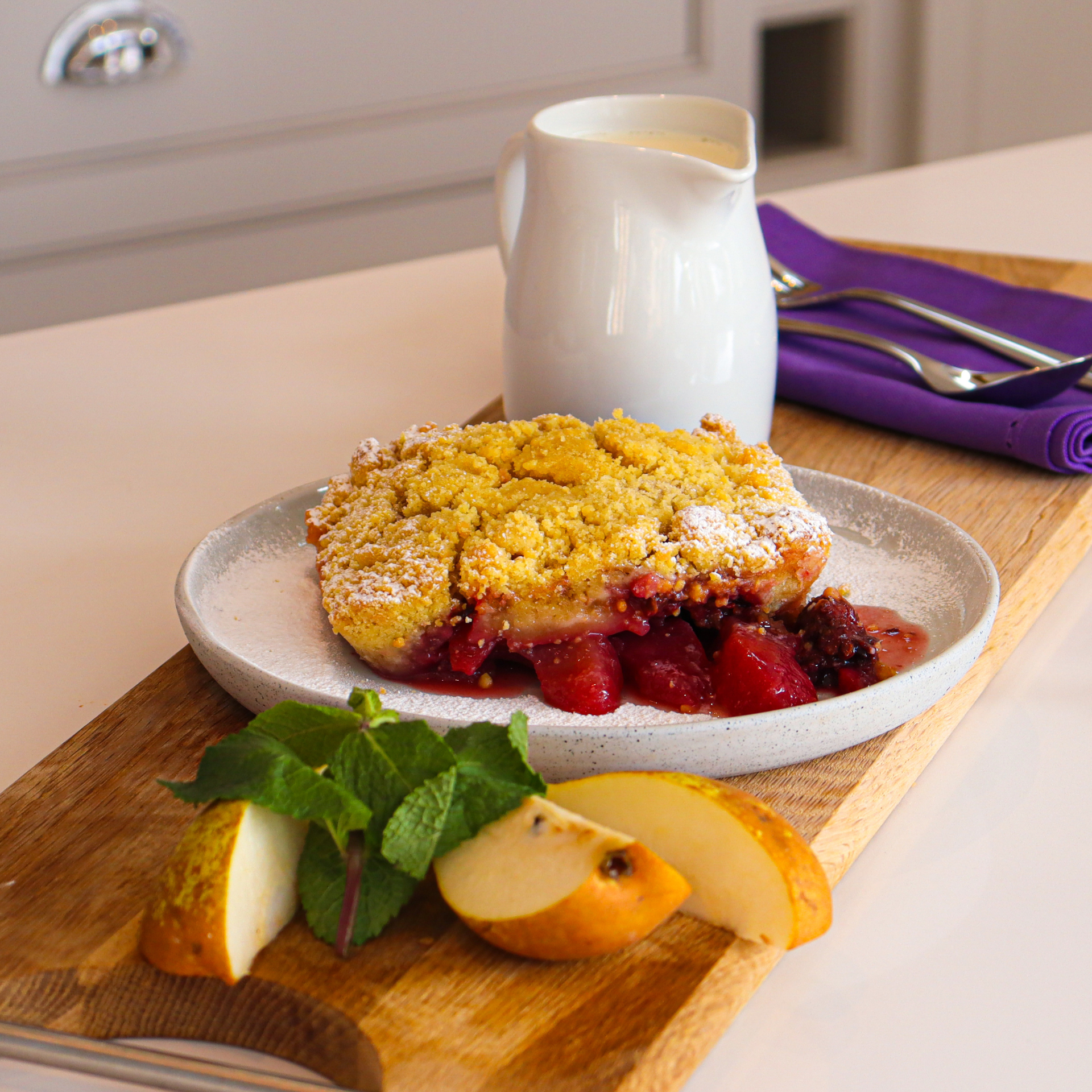 Pear and ginger crumble on a wooden board with a white jug