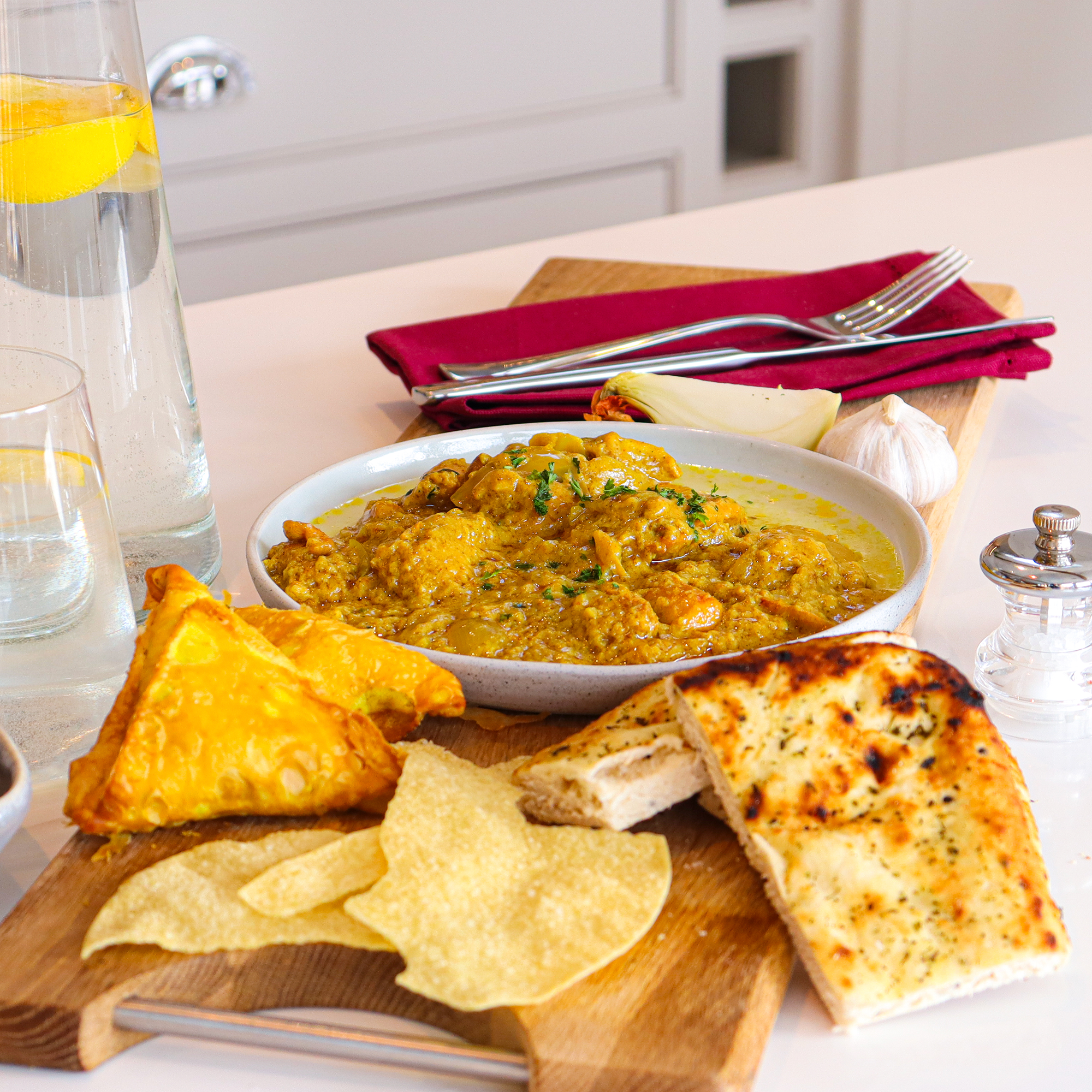 Sourced Meals Chicken Korma in a white bowl with naan bread and poppadoms