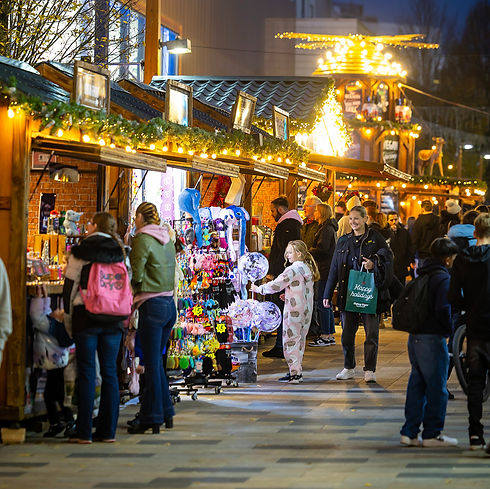 Atmospheric heritage-inspired outdoor Christmas market with warm glowing lights and traditional wooden cabins.