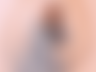 Ältere Frau sitzt nachdenklich auf einem Stuhl, rosa Hintergrund.