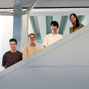 Performance photo titled SeaIslandFerry, featuring a classical music quartet on a light wooden stage inside a minimal concrete hall; a man plays a black grand piano on the left, a woman in a grey dress plays the clarinet, a man in a dark shirt plays the violin, and a man in a rust-orange shirt plays the cello, all illuminated by warm sunlight streaming through large windows.