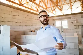 professional-man-holding-blueprints-in-unfinished-2026-01-05-06-21-10-utc.webp