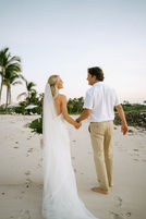 Happy couple holds hands, beach wedding