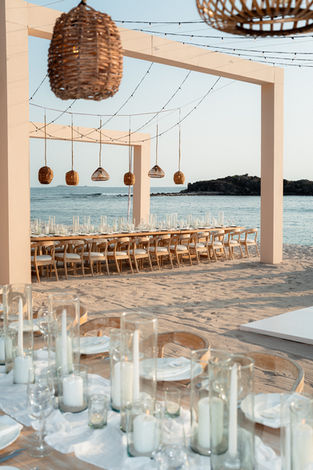 Beach wedding reception setup: long table, chairs, lights