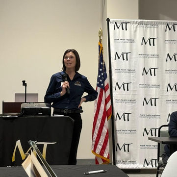 Kaylee Paffrath speaking on an economic development panel at the Mark Twain Regional Council of Governments Summit, standing at a podium with a microphone.