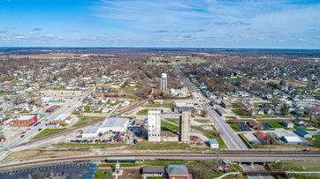 Aerial view of downtown Moberly, Missouri, showcasing residential areas, local businesses, railroad tracks, and prominent landmarks including a water tower, emphasizing the community's connectivity and infrastructure.