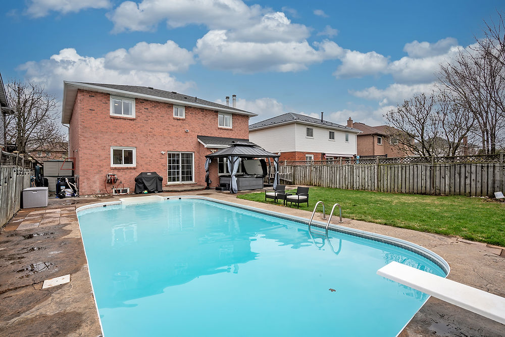 Backyard with a blue swimming pool and a brick house